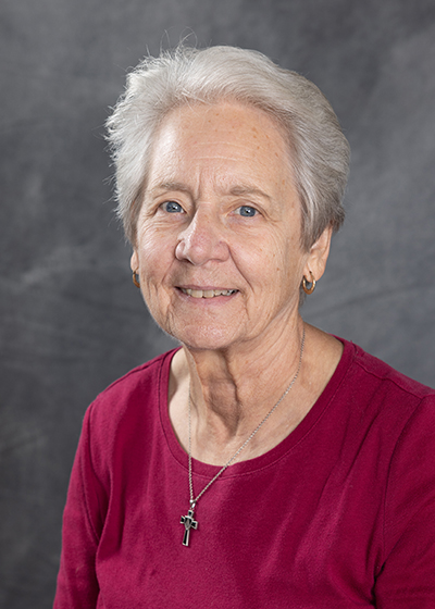 woman with short gray hair and a raspberry shirt