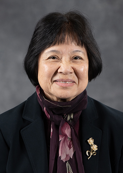 Asian woman with short black hair wearing a black blazer with a rose and burgandy scarf at her neck